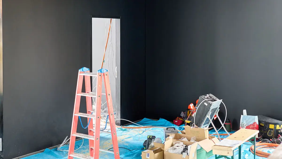 Room prepared for repair with a ladder, drop cloths and tools