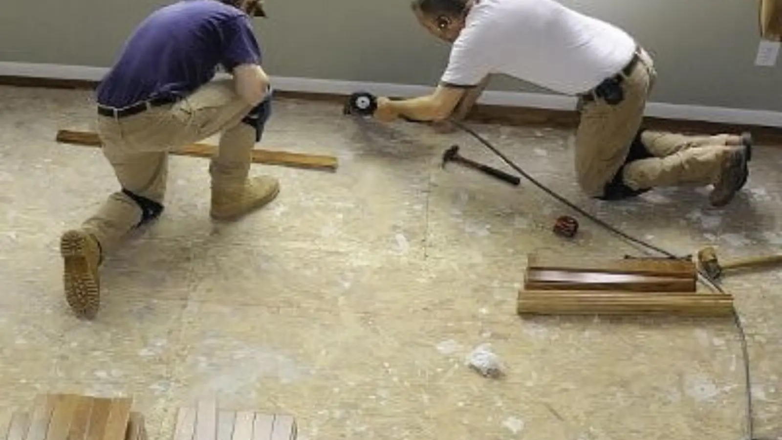 Two workers installing new flooring during water damage repair