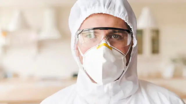 Person wearing a respirator, goggles and protective hood