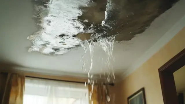 Water pouring through a damaged ceiling into a living room
