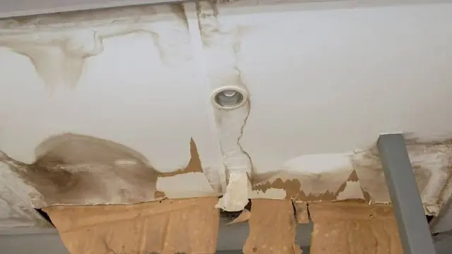 Water stained ceiling with mold growth around a pipe