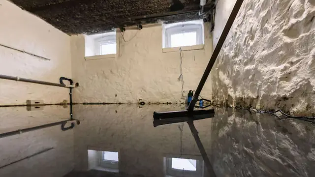 Flooded basement with a squeegee against the water